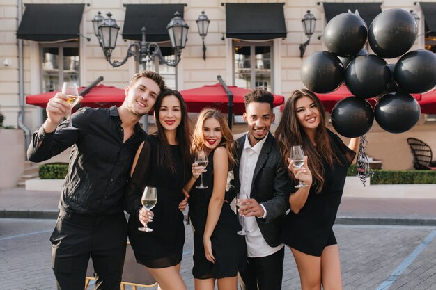 Fröhliche Freunde, die Champagner auf der Party im Freien trinken