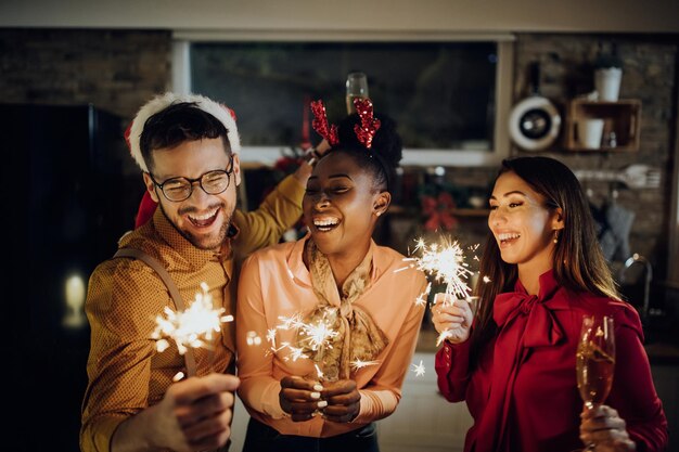 Fröhliche Freunde, die sich auf der Silvesterparty zu Hause mit Wunderkerzen amüsieren