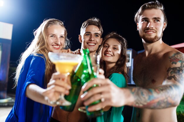 Fröhliche Freunde lächeln, freuen sich, ruhen sich auf der Party in der Nähe des Schwimmbades aus