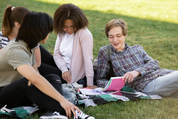 Fröhliche Gruppe multiethnischer Studenten, die im Freien studieren.