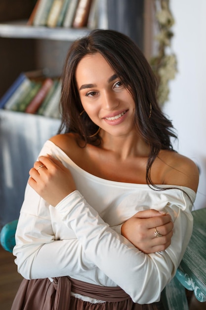 Fröhliche junge Dame, die auf einem Stuhl sitzt und lächelt Hochwertiges Foto