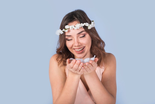 Kostenloses Foto fröhliche junge dame mit frischen blumen am kopf blumenblätter halten