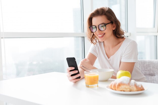 Fröhliche junge erstaunliche Frau, die durch Handy plaudert.