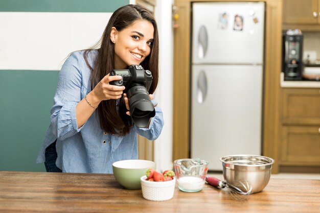 Fröhliche junge Food-Bloggerin, die mit einer professionellen Kamera Fotos für ihren Blog macht