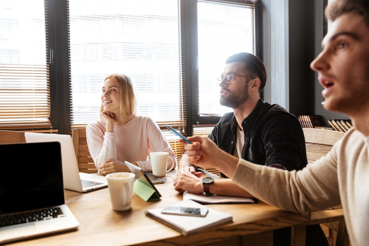 Kostenlose Foto fröhliche junge kollegen sitzen im büro