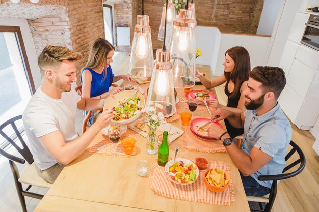 Fröhliche junge Leute, die das Abendessen genießen