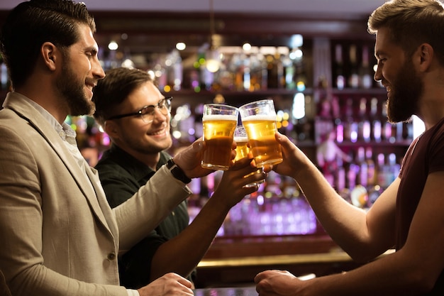 Fröhliche junge männer, die mit bier rösten