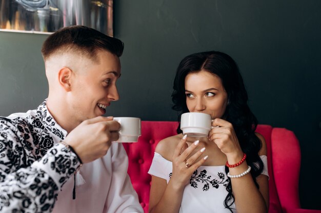 Fröhliche Jungvermählten stehen auf einem hellen rosa Sofa im Café still