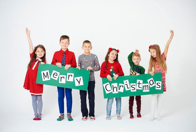 Fröhliche Kinder, die Weihnachtsdekoration halten