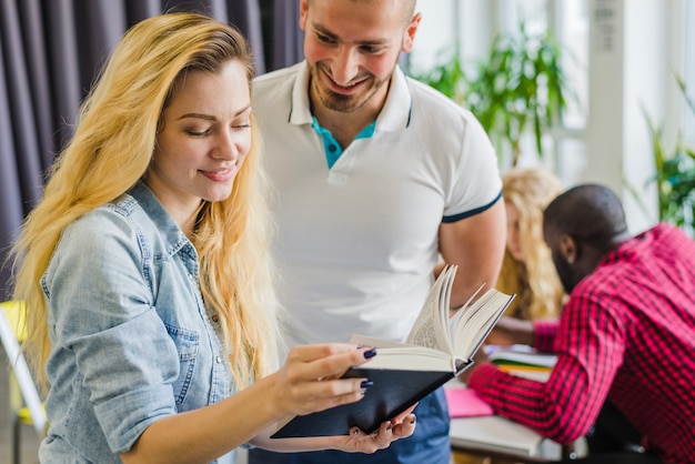 Fröhliche Klassenkameraden posieren mit Buch