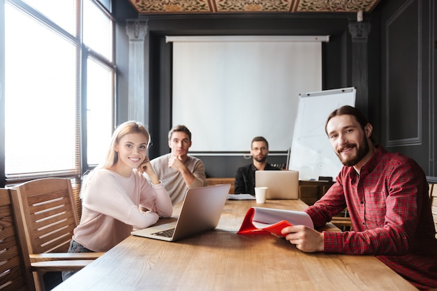 Fröhliche Kollegen sitzen im Büro