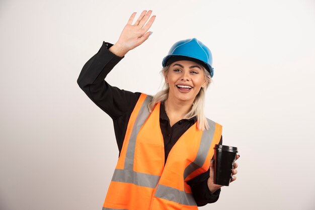 Fröhliche Konstruktion mit einer Tasse Tee, die jemanden winkt. Hochwertiges Foto