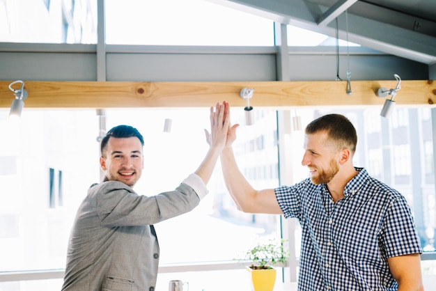 Fröhliche Männer, die im Büro fiving sind