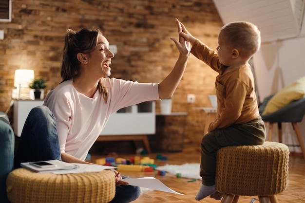 Fröhliche Mutter gibt ihrem kleinen Sohn zu Hause Highfive