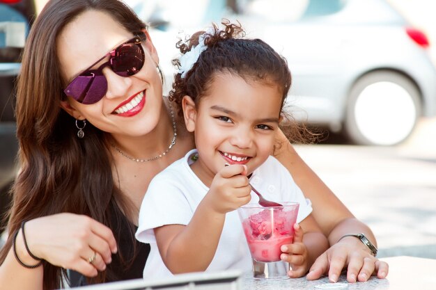 Fröhliche Mutter und Tochter essen Eis in einem Park