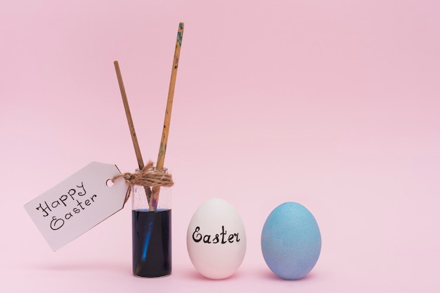 Fröhliche Ostern-Aufschrift mit Eiern und Pinsel
