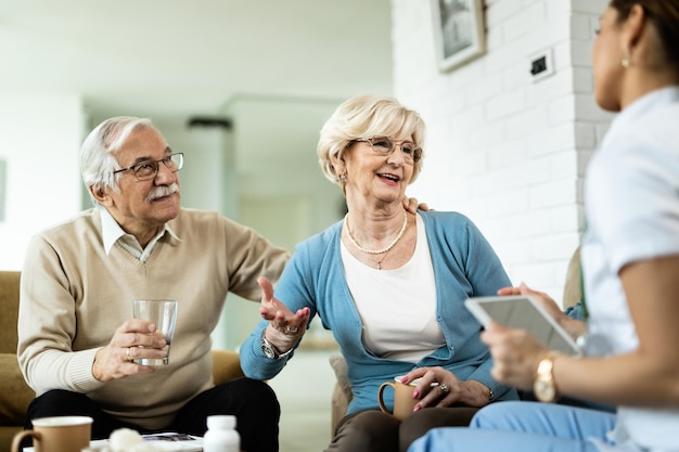 Kostenloses Foto fröhliche reife frau und ihr mann, die während des hausbesuchs mit dem gesundheitspersonal kommunizieren