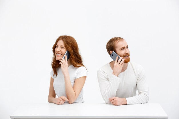 Fröhliche rothaarige Frau und Mann, sprechen Handy