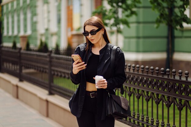 Fröhliche schöne brünette Frau in guter Laune verwenden Telefon außerhalb