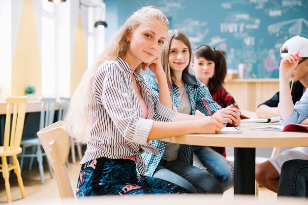 Fröhliche Schulmädchen sitzen am Desktop