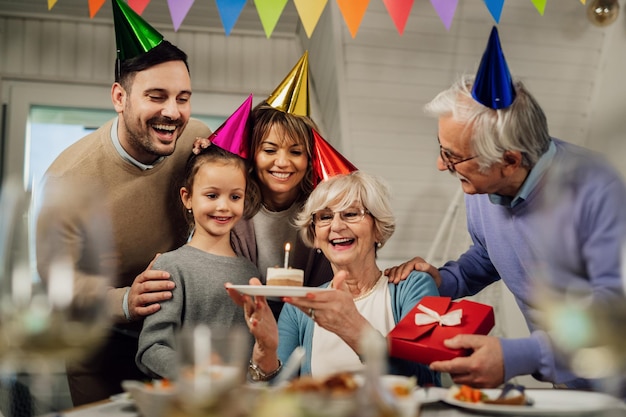 Fröhliche Seniorin und ihre Großfamilie haben Spaß, während sie ihren Geburtstag im Speisesaal feiern