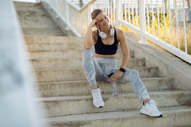 Fröhliche Sportlerin, die eine Pause macht und sich auf der Treppe entspannt