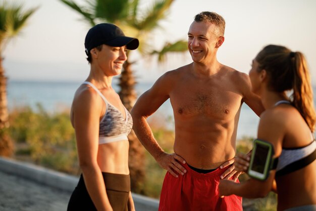 Fröhliche sportliche Freunde, die miteinander reden, während sie eine Pause vom Sport in der Natur machen. Der Mensch steht im Mittelpunkt.