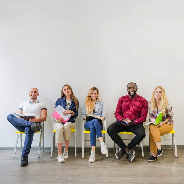 Fröhliche Studenten posieren mit Notizblöcken