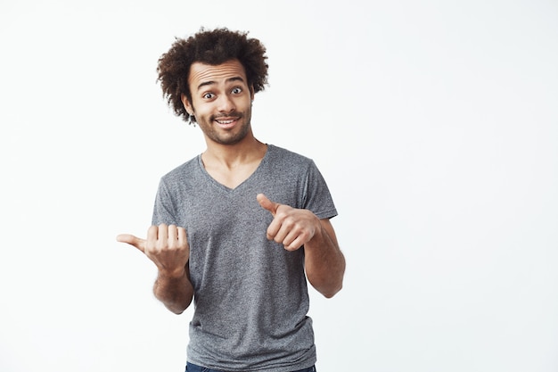 Fröhlicher afrikanischer Mann, der Finger in Seite zeigt.