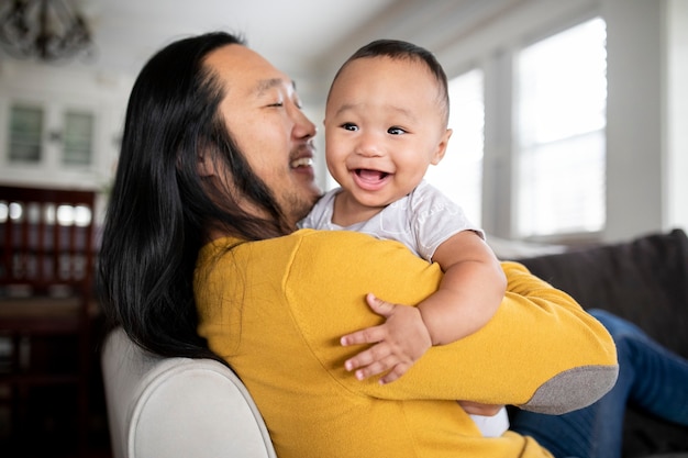 Fröhlicher asiatisch-amerikanischer Vater, der seinen Sohn umarmt