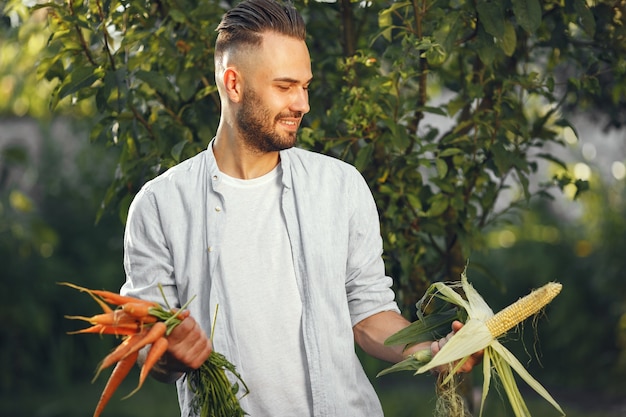 Fröhlicher Bauer mit Bio-Gemüse im Garten. Gemischtes Bio-Gemüse in Menschenhand.