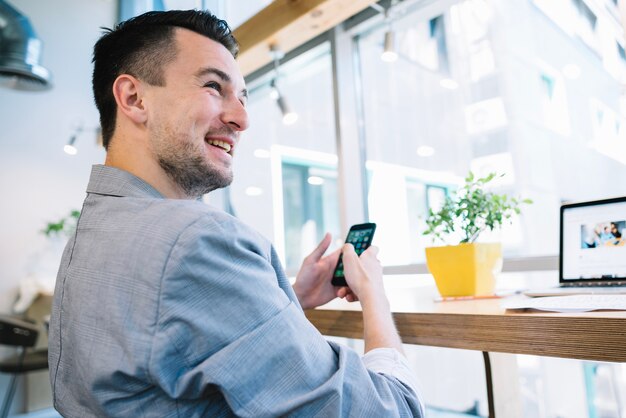 Fröhlicher Büroangestellter mit Telefon