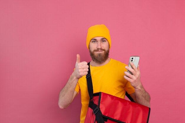 Fröhlicher europäischer Lieferbote mit Tasche lässig halten Telefon auf rosa