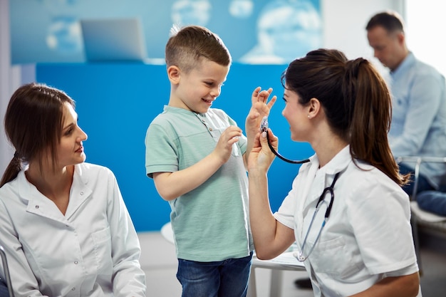 Fröhlicher Junge, der sich während eines Arzttermins in der Arztpraxis mit dem Kinderarzt amüsiert