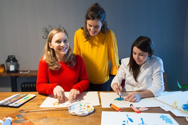 Fröhlicher Kunstlehrer und Studenten, die Malunterricht genießen