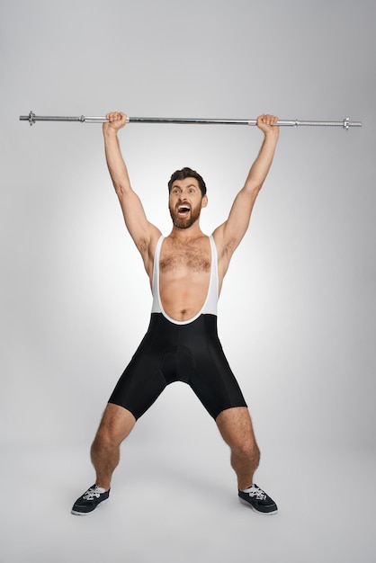 Kostenloses Foto fröhlicher männlicher powerlifter schreit beim heben einer unbeschwerten langhantel. vorderansicht eines fröhlichen athleten