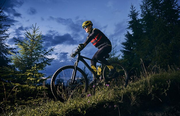 Fröhlicher männlicher Radfahrer, der nachts Fahrrad fährt