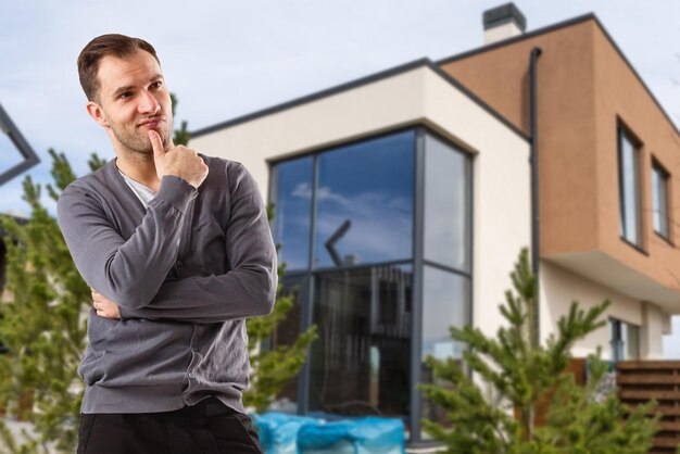 Fröhlicher Mann, der vor dem neuen Haus steht.