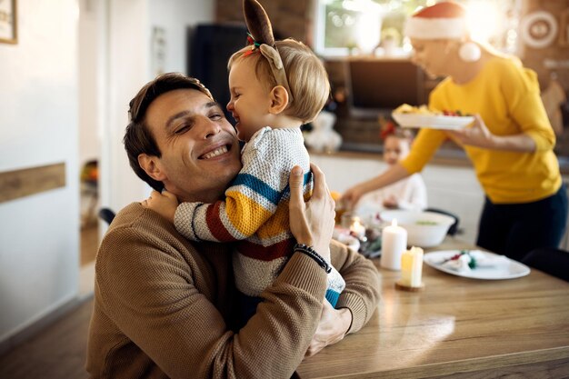 Fröhlicher Vater und sein kleiner Sohn umarmen sich am Weihnachtstag zu Hause