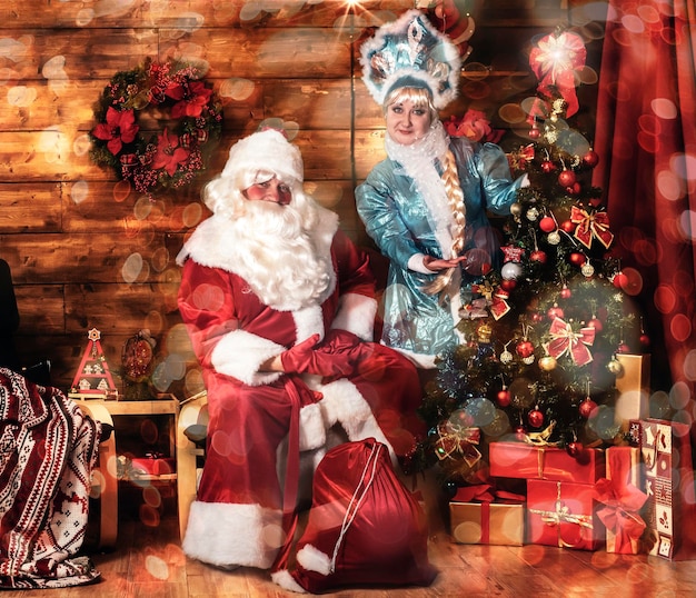 Fröhlicher weihnachtsmann mit schneewittchen und geschenken in einem weihnachtszimmer mit weihnachtsbaum