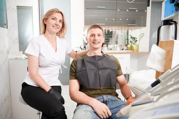 Fröhlicher Zahnarzt und Patient, der in der Zahnarztpraxis sitzt