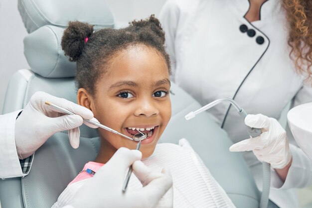 Fröhliches Afro-Kind bei regelmäßiger Zahnkontrolle in der Zahnklinik