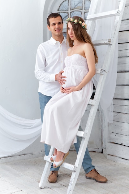 Fröhliches junges Paar gekleidet in Weiß, das zu Hause steht