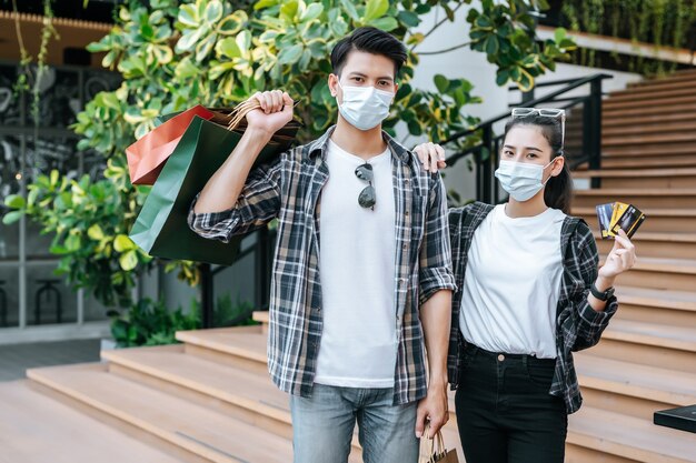 Fröhliches junges Paar in Maske mit mehreren Papiereinkaufstüten