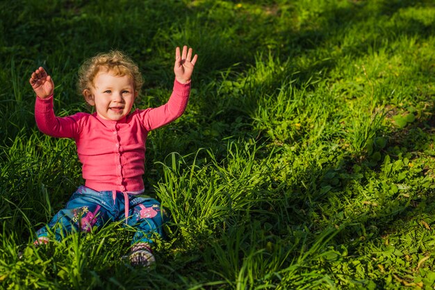 Kostenloses Foto fröhliches kind sitzt auf dem gras