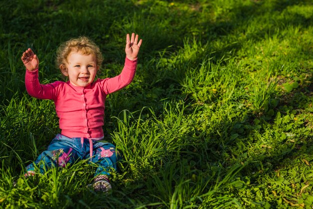 Fröhliches Kind sitzt auf dem Gras