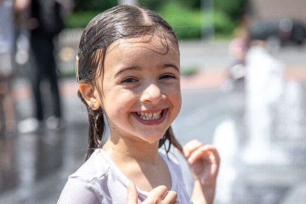 Fröhliches kleines Mädchen mit nassen Haaren im Freien an einem heißen Sommertag.