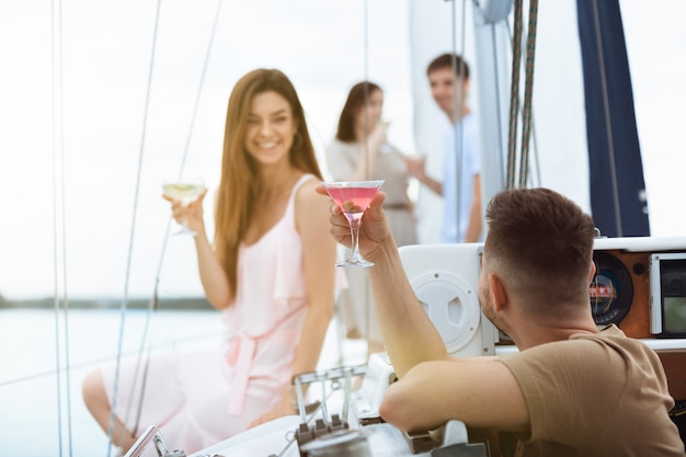 Fröhliches lächelndes Paar, das Wodka-Cocktails auf der Bootsparty im Freien trinkt, fröhlich und glücklich. Junge Leute, die Spaß am Seetour-, Jugend- und Sommerferienkonzept haben. Alkohol, Urlaub, Ruhe, Liebe.