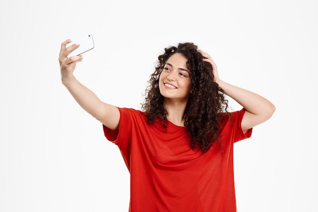 fröhliches lockiges Mädchen machen Selfie