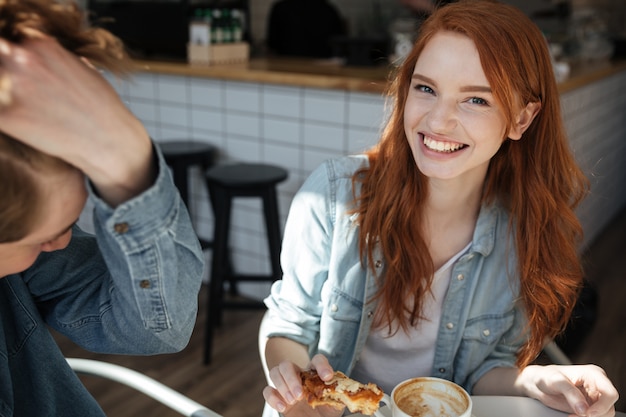 Fröhliches Mädchen, das Kamera im Café schaut